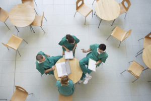 physicians sitting around a cafeteria table working on laptops